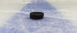 Hokejový puk ležící na modré čáře