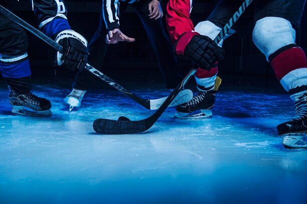 Rozhodčí vhazuje puk mezi dva hokejisty