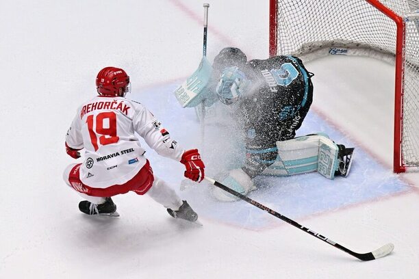 Karlovarský gólman Dominik Frodl kryje kotouč, vedle něj dotírající Patrik Hrehorčák